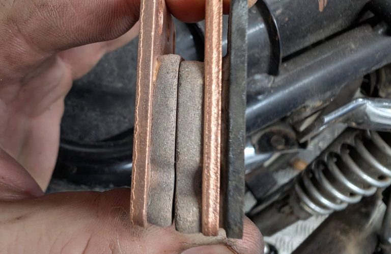 Close-up of a hand holding new set of brake pads comparing to the worn old brake pad